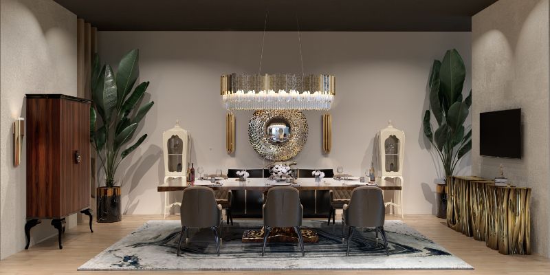 opulent dining room décor with gray area rug and gray dining chairs. a gold console table and round mirror.