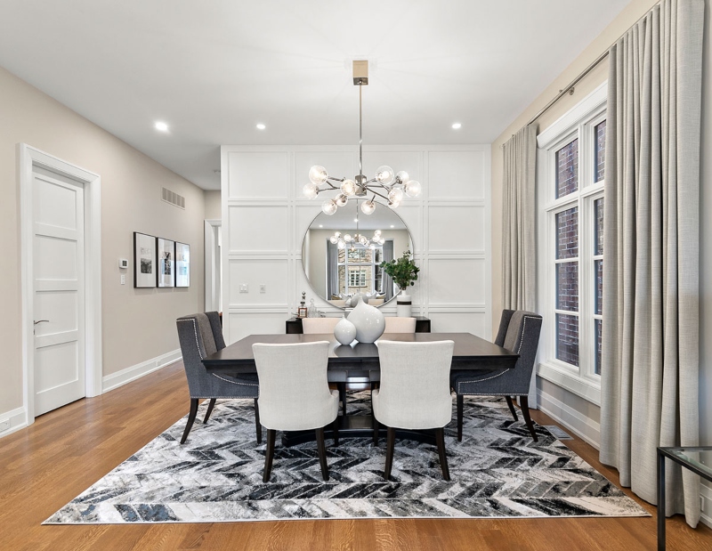 Rug Design Inspiration by Camden Lane Interiors. This white dining room has a black dining table, two dark grey armchairs, four white armchairs and a rug in white and grey colors.